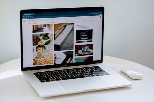 An open laptop showing the home screen of a website with 3 columns of photos.